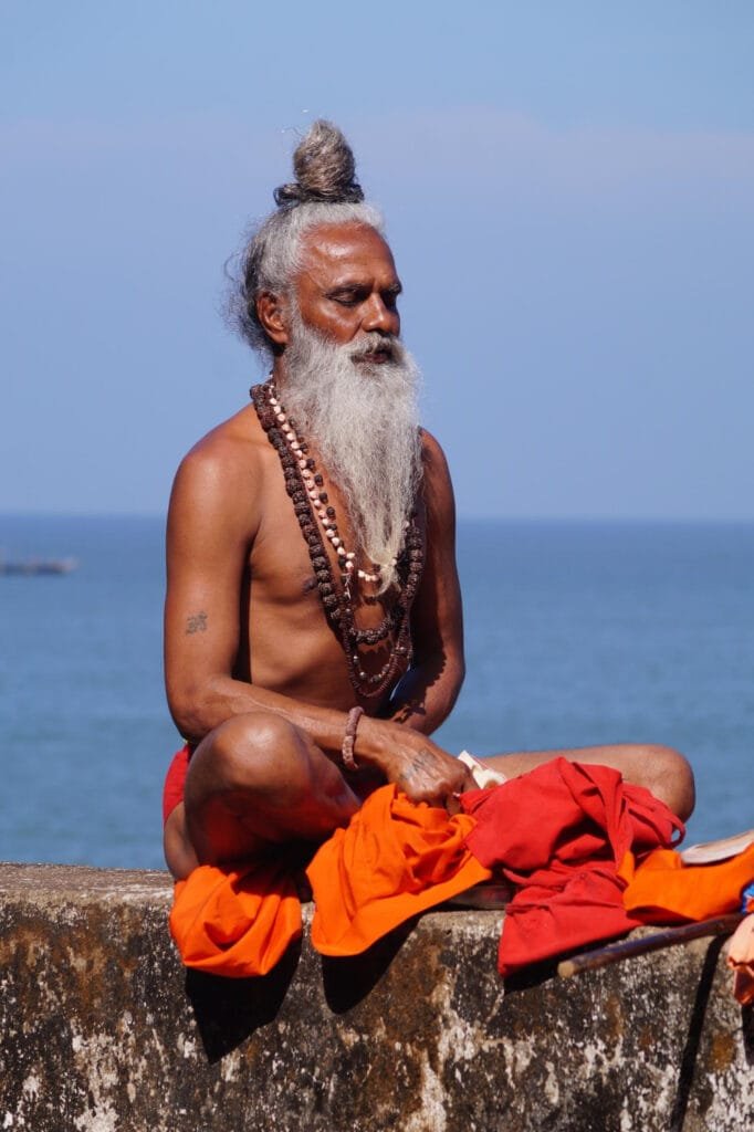 a man sitting on a ledge with a long beard and beads